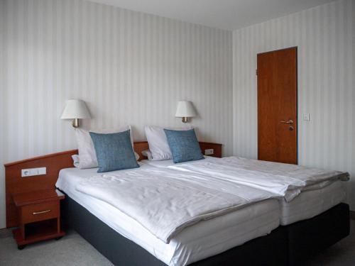 a bedroom with a large bed with blue pillows at Parkhotel in Bad Wünnenberg