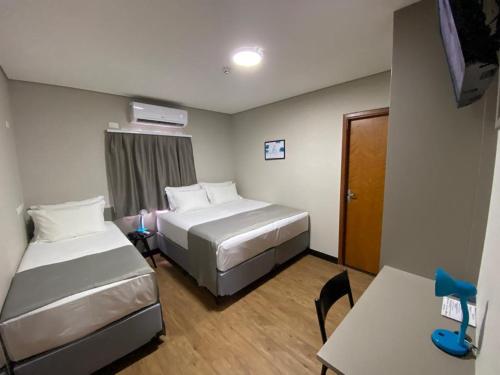 a hotel room with two beds and a table at Asa Hotel in Piracicaba