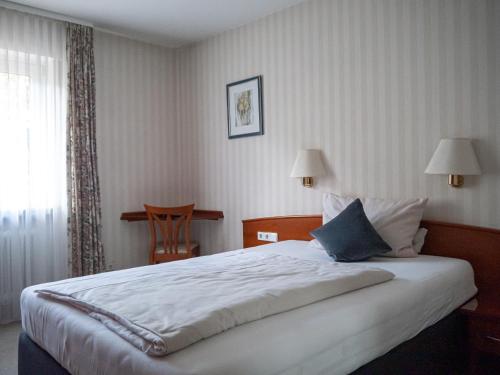 sypialnia z dużym łóżkiem i oknem w obiekcie Parkhotel w mieście Bad Wünnenberg