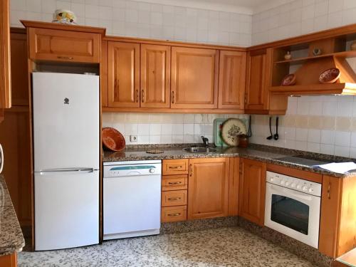 cocina con armarios de madera y nevera blanca en Casa Los Molineros en Cortes de la Frontera