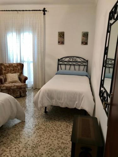 a bedroom with a bed and a chair at Casa Los Molineros in Cortes de la Frontera