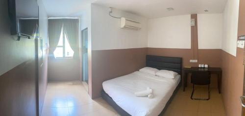 a small bedroom with a bed and a desk with a window at Lih Pin Hotel in Sungai Petani