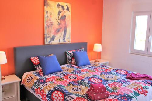 a bedroom with orange walls and a bed with blue pillows at Casa Colorida in Porches