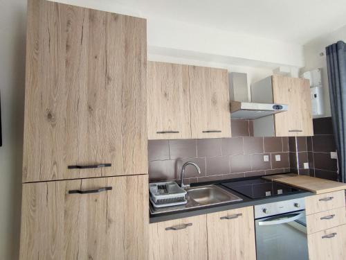 une cuisine avec des armoires en bois et un évier dans l'établissement L'Ambre d'Or, à Falicon