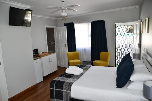 a bedroom with a white bed and two yellow chairs at Friendz Guesthouse in Knysna