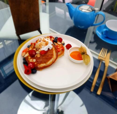 a plate of breakfast food with french toast and fruit at The Blue Horse Suite at The Grumpy Schnauzer B&B Private Hot Tub, Gym, Breakfast, Stunning! in Airdrie