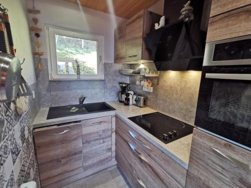uma cozinha com armários de madeira, um lavatório e um fogão em les Genêts em La Bresse