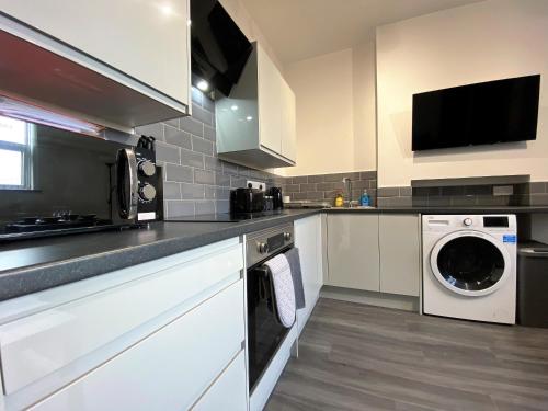 a kitchen with a washing machine and a washer at StayCrewe Apartments in Crewe