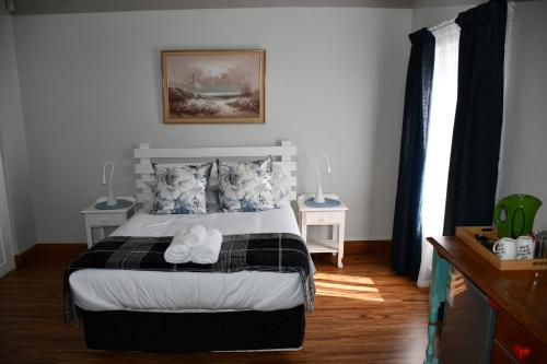 a bedroom with a bed with two nightstands and two windows at Friendz Guesthouse in Knysna