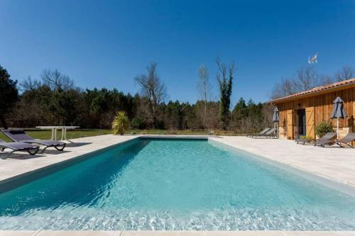 - une piscine avec une terrasse et une maison dans l'établissement Domaine de la grange, à Carcans
