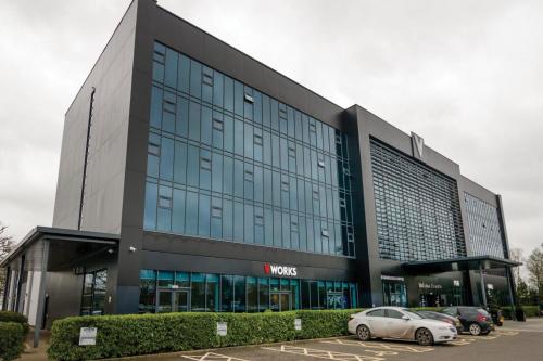 a large building with cars parked in a parking lot at Village Hotel Manchester Ashton in Ashton under Lyne