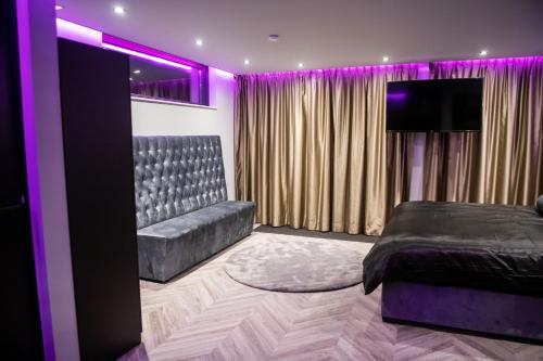 a bedroom with a bed and a couch and purple lighting at Royal Suite in 's-Gravenzande