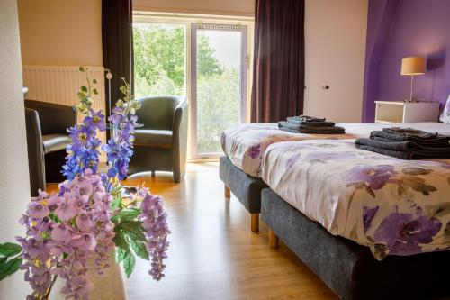 a hotel room with two beds and purple flowers at Het Groene Wout in Goudriaan