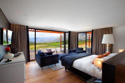 a bedroom with a bed and two chairs and a balcony at Clouds Estate in Stellenbosch