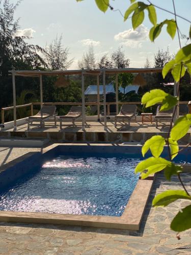 a pool with chairs and a wooden bridge over it at Zanzibar Tropical Sunset Boutique Hotel - Adults Only in Kiwengwa
