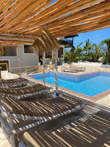 a large swimming pool with a wooden pergola at Zanzibar Tropical Sunset Boutique Hotel - Adults Only in Kiwengwa