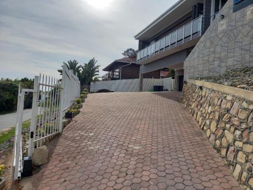 a brick walkway next to a building with a fence at Friendz Guesthouse in Knysna