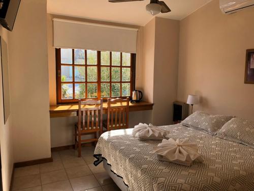 a bedroom with a bed and a desk and a window at Hotel Lihuel in Villa Carlos Paz