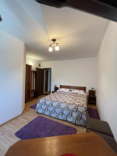 a bedroom with a large bed with purple rugs at Pensiunea La Steaguri in Pojorâta
