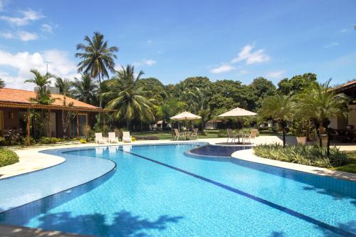 a swimming pool with chairs and umbrellas at a resort at Pousada Recreio Casa Grande in Cascavel