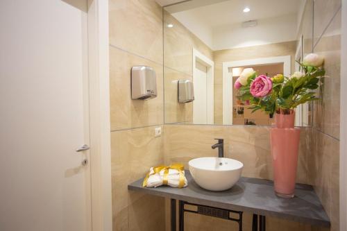 a bathroom with a sink and a vase with flowers at Hotel Flora in Alba Adriatica