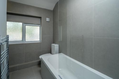 baño blanco con bañera y ventana en Skyline Serviced Apartments - Flat B Rockingham Way en Stevenage