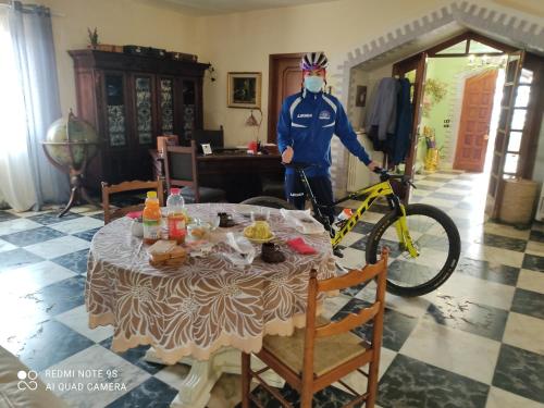 a man with a mask standing next to a table with a bike at La Gallina Nel Castello in Albenga