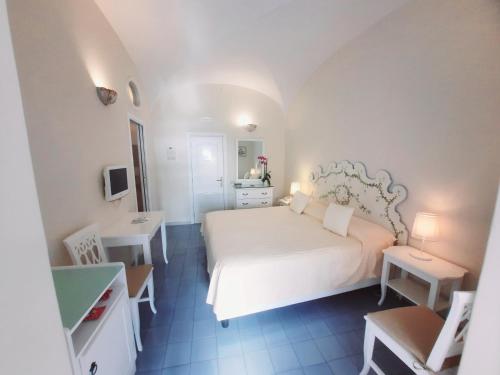 a white bedroom with a white bed and a table at Villa La Tartana in Positano