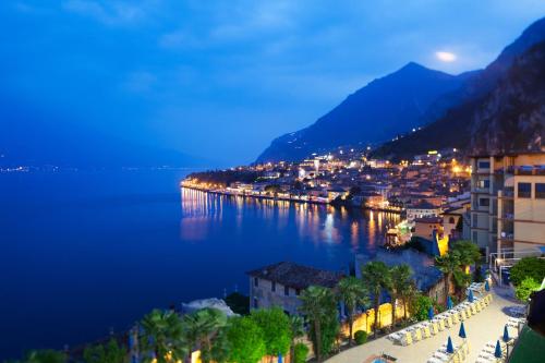a view of a town by the water at night at Hotel Splendid Palace in Limone sul Garda