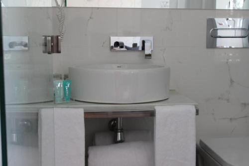 - Baño con lavabo blanco y 2 toallas en Hotel Boutique Caireles, en Córdoba