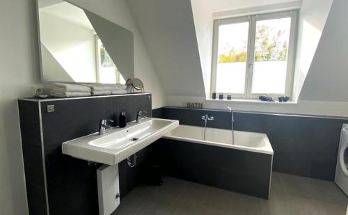 a bathroom with a sink and a tub and a mirror at PRIMA Inn Ferienwohnungen Sonnenufer am Ruppiner See in Neuruppin