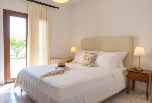a bedroom with a white bed with a large window at Aegean Blue Horizon in Afitos