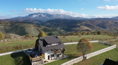 une vue aérienne sur une maison avec des montagnes en arrière-plan dans l'établissement Utopia Mountain resort Bjelasnica, à Bjelašnica