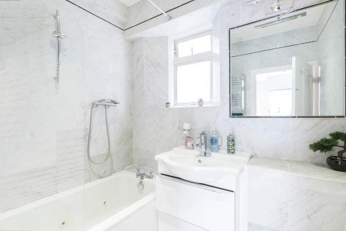 La salle de bains blanche est pourvue d'un lavabo et d'un miroir. dans l'établissement Marylebone Mews - Beautiful 2 bedroom flat, à Londres
