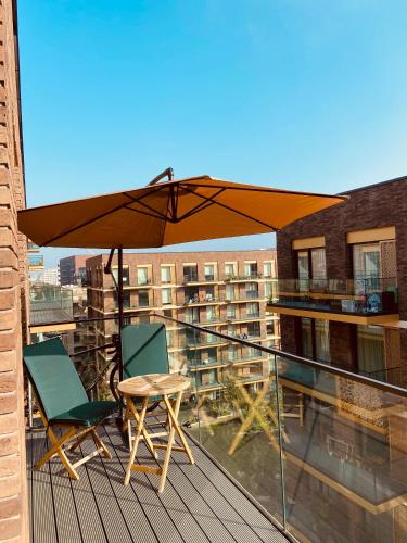 een balkon met een tafel, 2 stoelen en een parasol bij Royal Wharf by the Thames in Londen