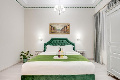 ein Schlafzimmer mit einem grünen Bett und einem Kronleuchter in der Unterkunft Pandrosos Divine Suites in Athen