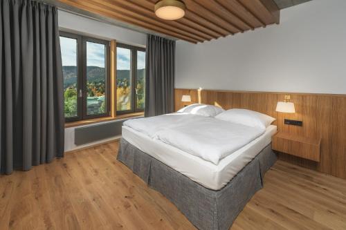 1 dormitorio con 1 cama grande y ventanas en Palace Apartments en Špindlerův Mlýn