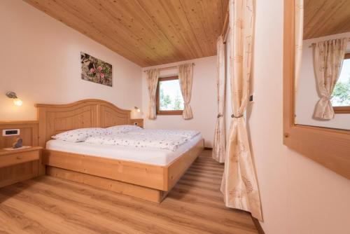 una camera con letto e pavimento in legno di Apartments La Rives a Santa Cristina in Val Gardena