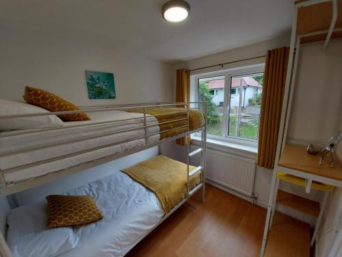 two bunk beds in a room with a window at Troodos in Llandudno