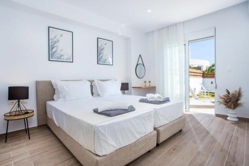 una camera bianca con un grande letto e un balcone di Rhodian Dunes Villas a Kiotari