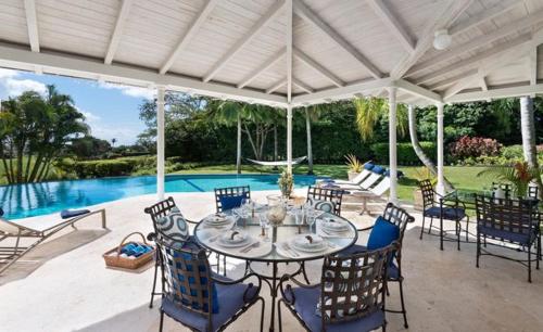 a patio with a table and chairs and a pool at Royal Westmoreland - Villa Rosa by Island Villas in Saint James
