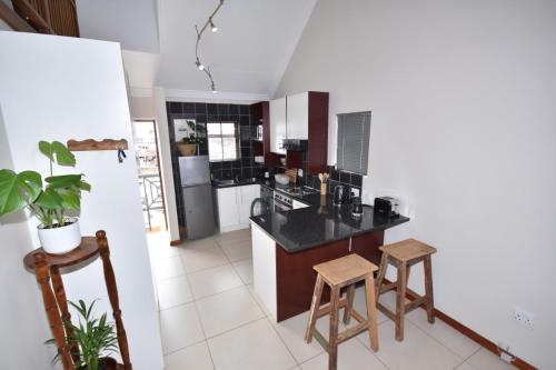 a kitchen with a black counter top and wooden stools at Cyprus Manor 12 in Mossel Bay