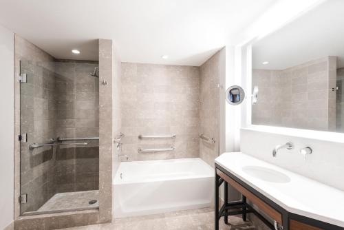 a bathroom with a shower and a tub and a sink at The Heathman Hotel Kirkland in Kirkland