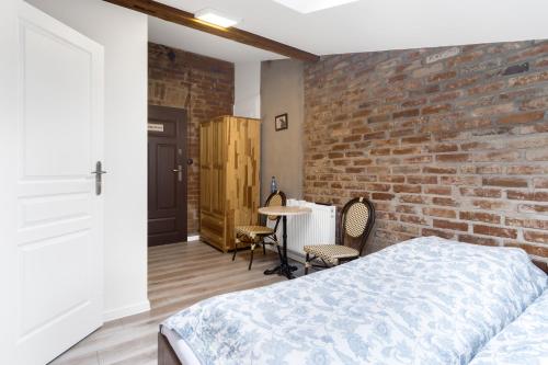 a bedroom with a brick wall and a bed and a table at Kawerna Obornicka Pod Orłem Noclegi in Oborniki