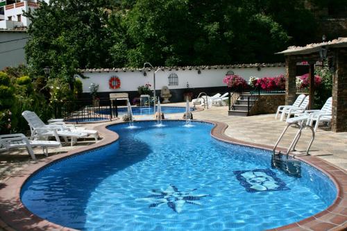 a large swimming pool with white chairs in a yard at Alojamientos Rurales Benarum con Spa in Alpujarra De La Sierra
