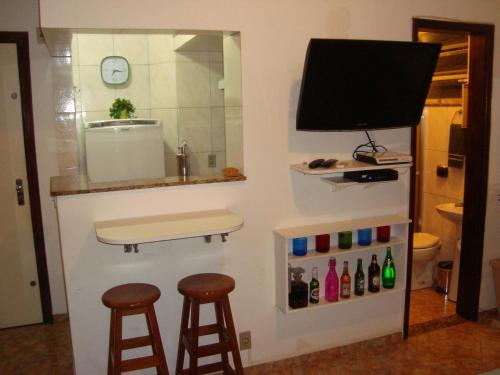 um bar com dois bancos e uma televisão na parede em Apart Marcelo - Studio Copacabana no Rio de Janeiro