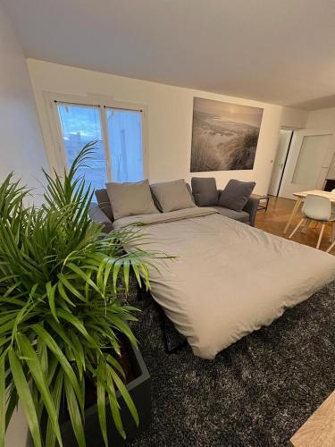 - un grand lit dans une chambre avec un canapé et des plantes dans l'établissement New&Cosy - Near Disney/Paris - 100m RER A, à Lognes