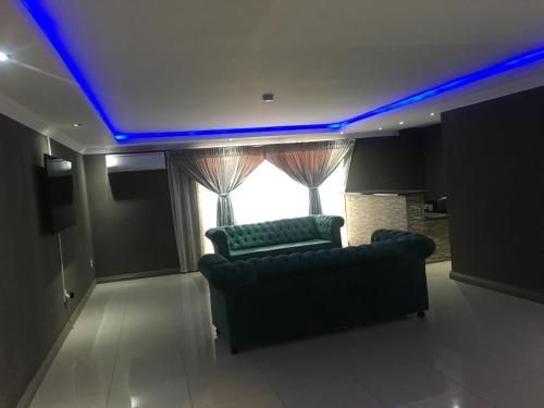 una sala de estar con 2 sofás y un techo de LED azul en President Guest Lodge, en Louis Trichardt