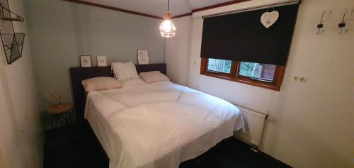 Schlafzimmer mit einem Bett mit weißer Bettwäsche und einem Fenster in der Unterkunft Chalet 11, in het bos in Doornspijk