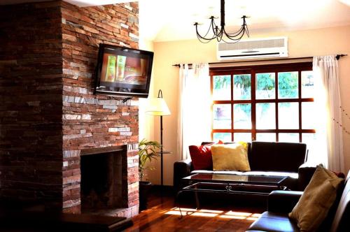 a living room with a couch and a tv on a brick fireplace at Ayres House in Colonia del Sacramento